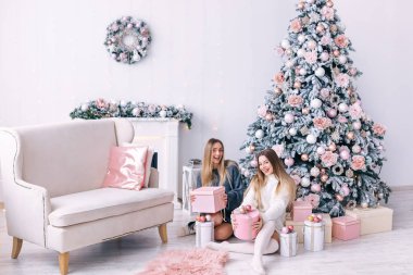 Gülümseyen genç kadınlar güzel bir Noel 'e yakın bir hediye kutusu açıyor. 