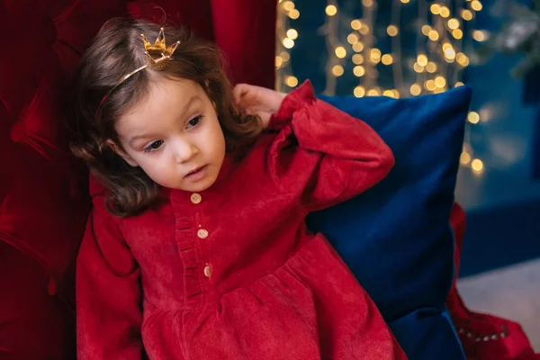 Close-up van een meisje in een rode jurk op een rode fauteuil op de rug gr — Stockfoto