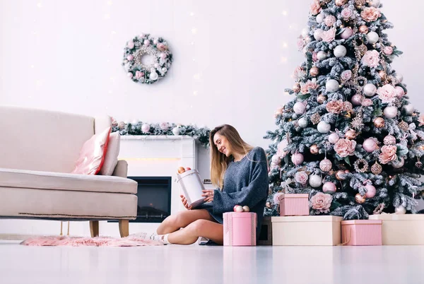 Chica en un suéter gris posa cerca de los árboles de Navidad decorados — Foto de Stock