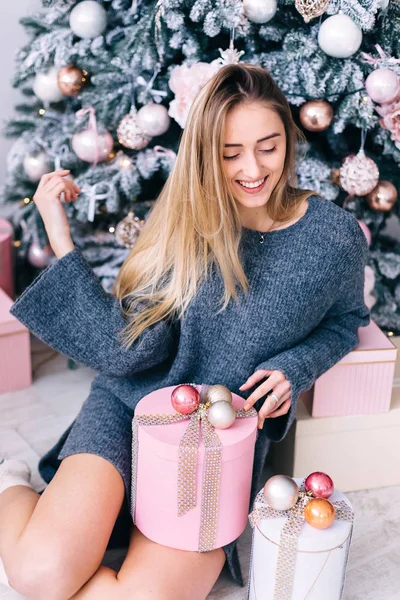 Ragazza in maglione grigio posa vicino regali e albero di Natale. studio — Foto Stock