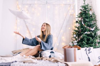 Kız yatağa oturur ve bir yastık atar. Yatağın üstünde. Ch