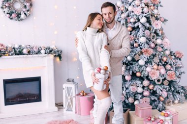 Adam yeteneği olan bir kıza sarılıyor. Noel ağacı olan rahat beyaz bir oda.