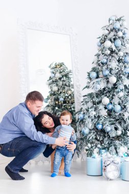 Küçük çocuk bir hediye tutuyor. aile Noel ağacının yanında ve büyük 