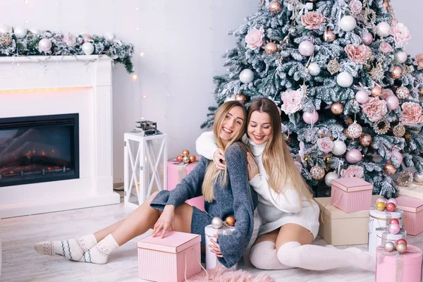 Ευτυχισμένοι φίλοι ποζάρουν κοντά στο χριστουγεννιάτικο δέντρο στο στούντιο. Τα κορίτσια χαμογελούν — Φωτογραφία Αρχείου