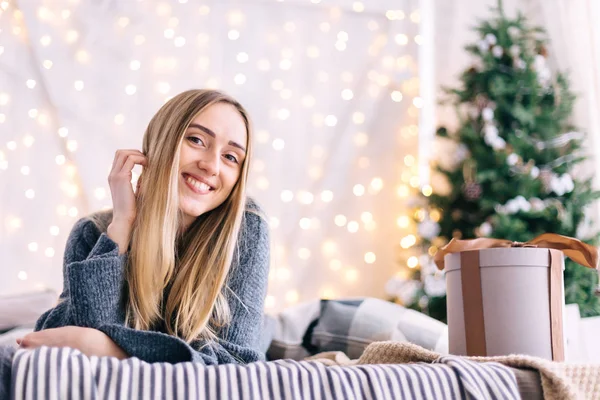 Menina deita-se na cama e sorrir. Árvore de Natal e grinaldas em t — Fotografia de Stock