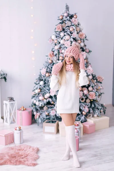 Ragazza in un maglione bianco e cappello rosa, sciarpa e guanti guarda int — Foto Stock