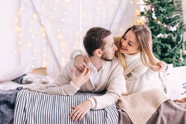 boyfriend and girlfriend are lying on the bed and looking at eac