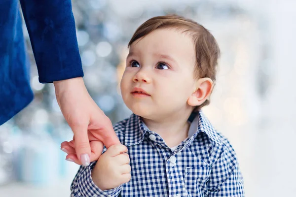 Little boy hold hand of his mother. Blurred Christmas tree and g — Stock Photo, Image