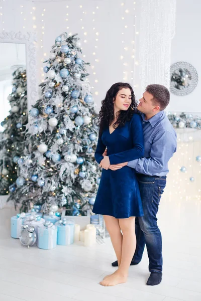 Casal apaixonado abraçando perto da árvore de Natal e grande espelho. Olha. — Fotografia de Stock