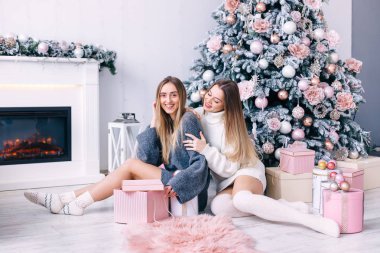 Stüdyoda, hediyelerin arasında yerde oturan mutlu arkadaşlar.