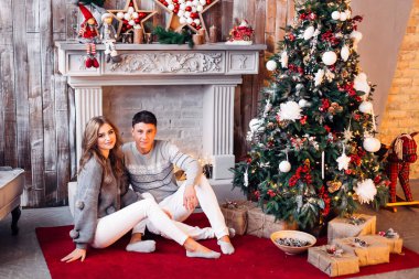 Noel 'in yanında şöminenin yanında oturan mutlu gençler.