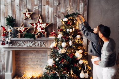 Süslü şöminesi ve Noel ağacı olan rahat bir oda. Bu adam...