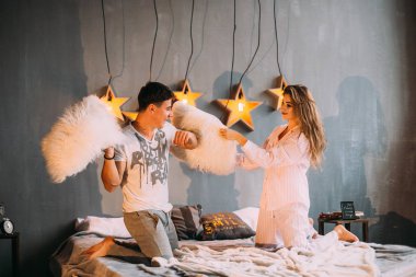 Erkek ve kız yatak odasına yastık attılar. şık bir yatak odası.