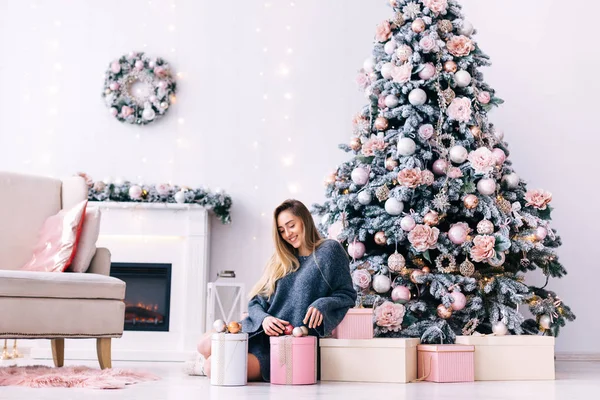 Fille assise sur le sol parmi les cadeaux près du sapin de Noël. c — Photo