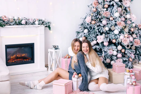 Ευτυχισμένοι φίλοι ποζάρουν κοντά στο χριστουγεννιάτικο δέντρο στο στούντιο. Τα κορίτσια χαμογελούν — Φωτογραφία Αρχείου