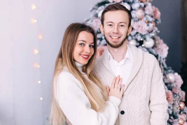 Casal apaixonado em camisolas de malha branca na árvore de Natal backg — Fotografia de Stock