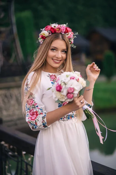 Noiva em um belo vestido bordado com uma coroa de flores na cabeça — Fotografia de Stock
