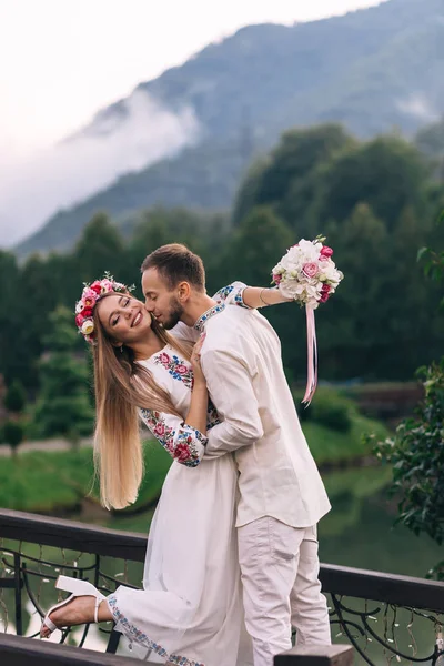 Brudgummen kramar och kysser bruden. nygifta på bakgrunden — Stockfoto