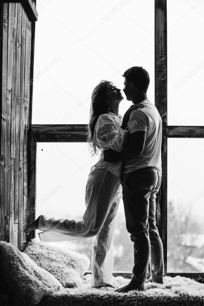 guy and girl are standing on the windowsill in each other's arms