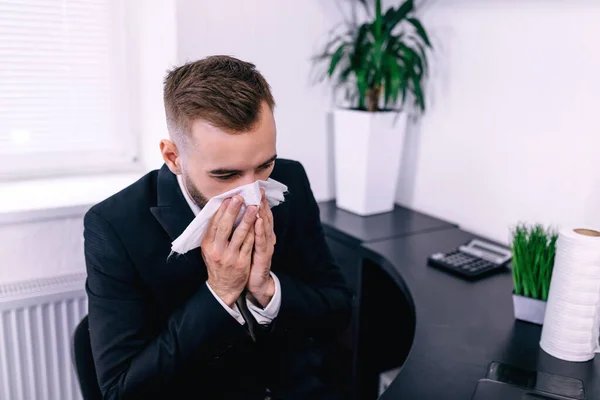 sick entrepreneur blowing in a wipe at office feeling sick and tired