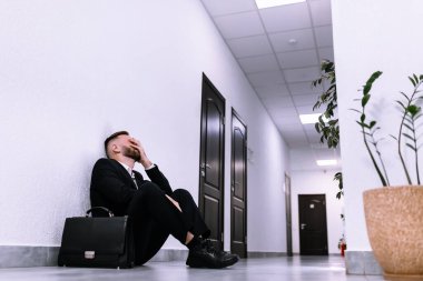 İş başarısızlığı ve işsizlik sorunu kavramı. Toka başı, işsiz bir işadamı bir ofisin koridorunda tek başına oturuyor..