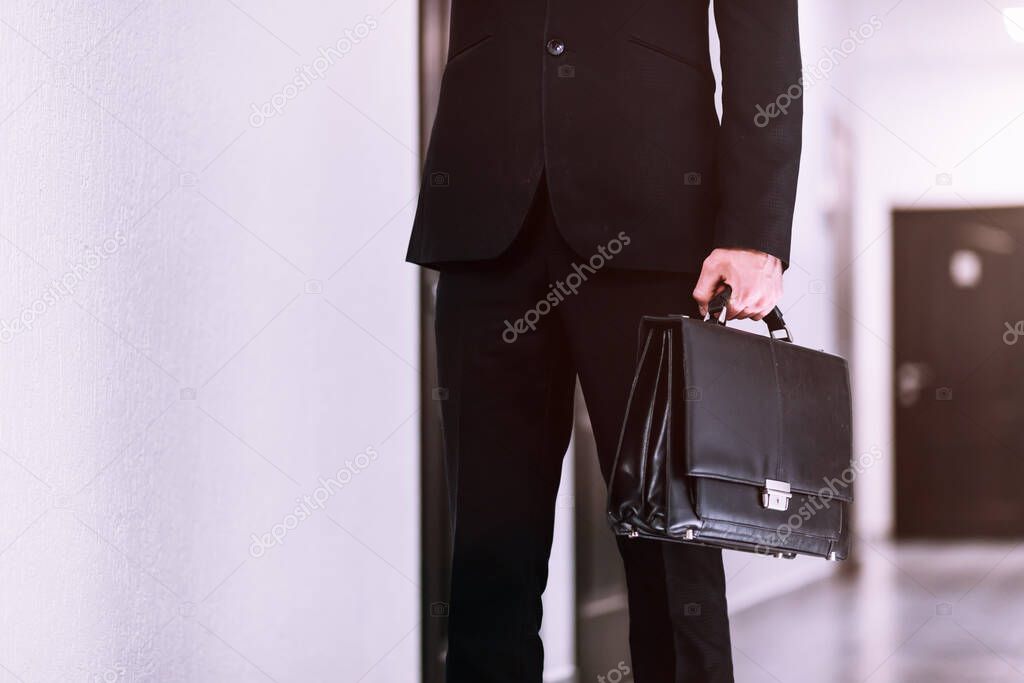 closeup businessman holding briefcase on corridor office