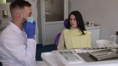 Erkek dişçi maske takıyor, stomatoloji aletleri alıyor ve prosedüre hazırlanıyor, modern klinik, sağlık hizmetleri