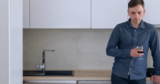 一个混淆不清的男人站在厨房里喝酒 — 图库视频影像