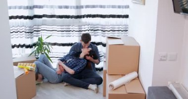 Yeni dairede kutularla yerde öpüşen çift.