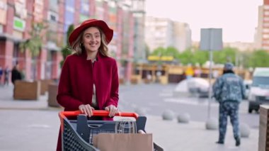 Alışveriş arabasında gezen güzel bir genç kız açık hava alışveriş merkezinin otoparkına taşınıyor.