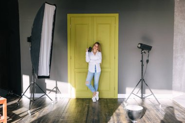 Fotoğraf dersleri için bayan eğitmen stüdyoda kamera ve hafif ekipmanla bekliyor.