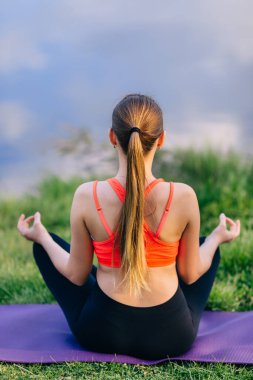 Yogacı kız yazın meditasyon yapan kadını dışarıda dinlendiriyor. Nilüfer çiçeğinde oturan güzel beyaz model..