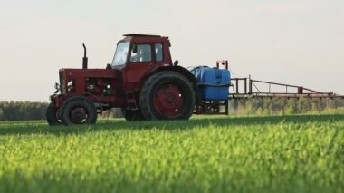 Tarla ilaçlarına ve böcek ilaçlarına tarım traktörü sıkmak, yeşil tarlalara böcek ilacı sıkmak, tarımsal doğal bahar işleri..