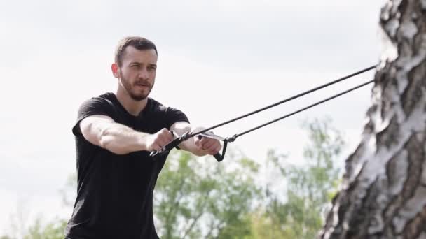 Muskelkräftiger Hemdsloser Mann Trainiert Seine Arme Mit Einem Gummiband — Stockvideo