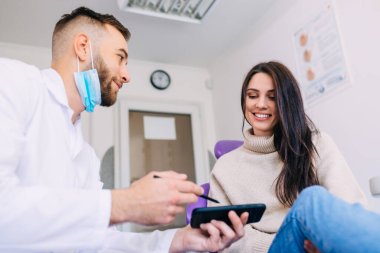 Ortodontist elinde çene röntgeni olan bir telefon tutuyor ve kadın hastaya gösteriyor. orthopantomogram.