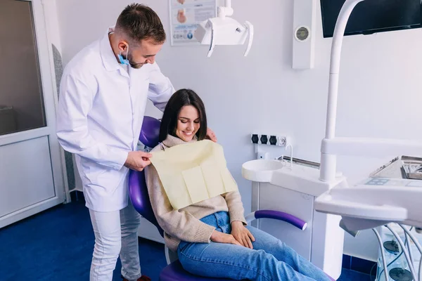 牙医让病人在诊所接受体格检查 漂亮的病人坐在牙椅上笑着 — 图库照片