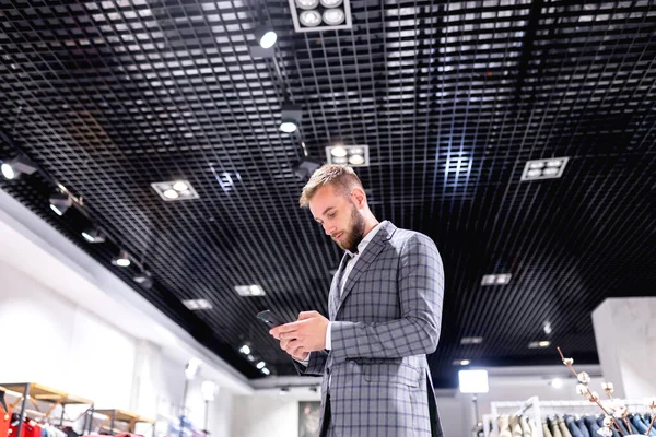 Joven Usando Smartphone Tienda Ropa —  Fotos de Stock