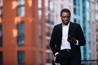 Genç işadamı web kamerasına cep telefonuna bakıyor.