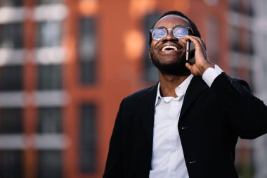 Genç stil sahibi adam telefonda konuşuyor ve gülümsüyor.