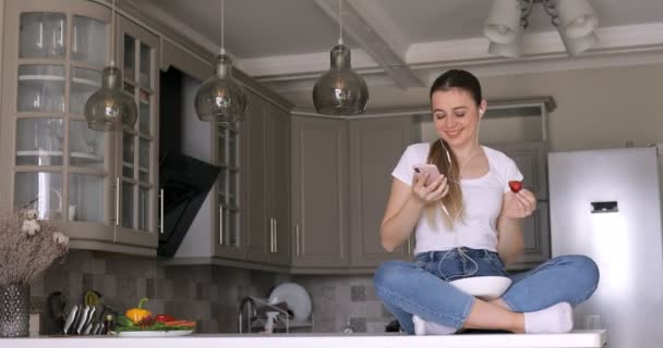 Mulher Cozinha Com Fones Ouvido Ouvir Música Comer Morango Casa — Vídeo de Stock