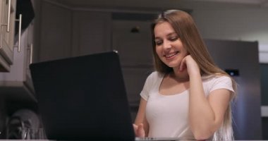 Güzel, beyaz bir kız mutfakta oturmuş dizüstü bilgisayarına bakıyor, video kaset ya da internetten özel ders alıyor, bir internet bloğu kaydediyor, şirin bir model web kamerasına bakıyor ve 4k görüntülerinden bahsediyor.