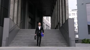 Evrak çantalı, neşeli ve başarılı bir iş adamının portresi. Komik bir şekilde dans ediyor ve ofisten çıkarken sevinçten zıplıyor.