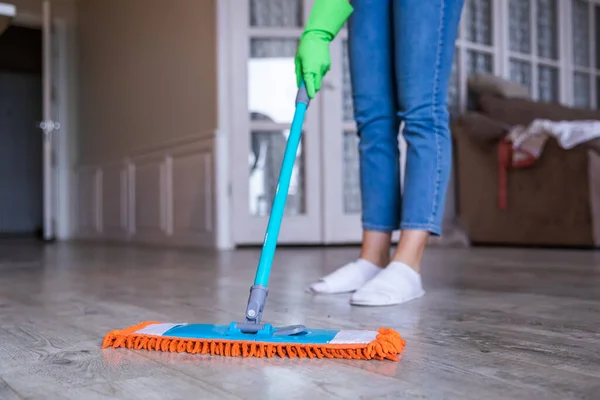 A professional cleaner with gloves washes the dirty floor with a mop.