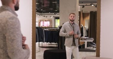 Ceket deneyen bir iş adamı, aynada kendine bakıyor, moda mağazası, perakende mağazası, butik marka kıyafetler.