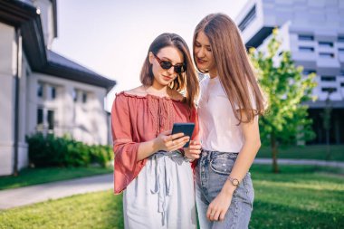 Şok olmuş kız öğrenci kız kardeşlerin telefonlarına bakarken çekilmiş güzel bir fotoğraf..