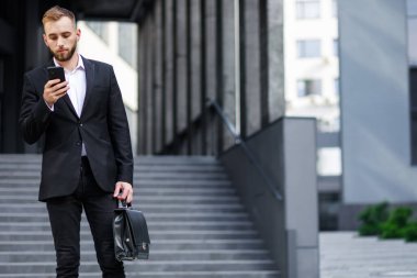 Takım elbiseli genç adam akıllı telefon kullanıyor. 