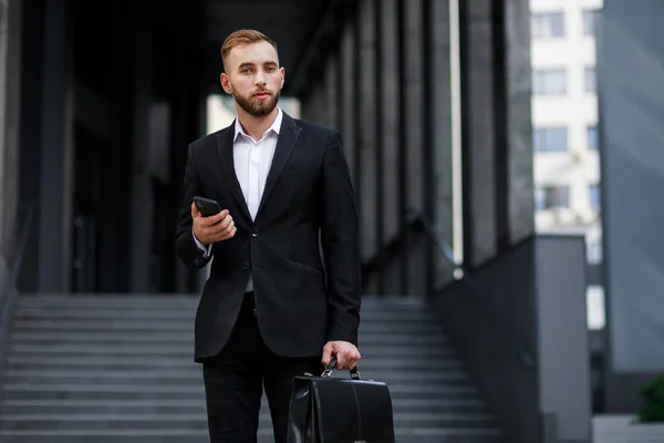 Resmi Takım Elbiseli Genç Adam Evrak Çantası Akıllı Telefon Tutuyor — Stok fotoğraf