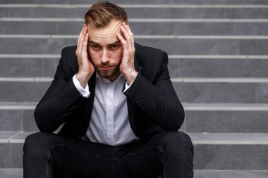 Resmi takım elbiseli, çaresiz bir gencin portresi.