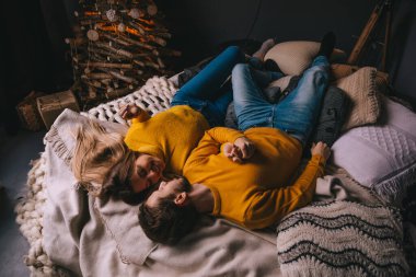 Mutlu çift yatakta uzanıyor ve evde birlikte dinleniyorlar. Romantik çift birbirine bakıyor ve kış tatili boyunca dinleniyor..