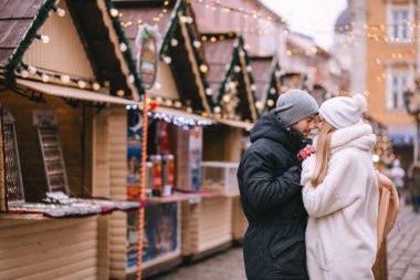 Erkek ve kadın, Noel 'e kadar süslenmiş pazar meydanında kucaklaşıyorlar. Noel, tatil, tatil, aşk konsepti.